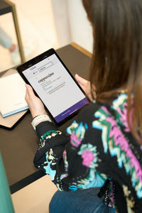Een student is over een tablet gebogen met een schermafbeelding van Van Dale Online met de definitie van het woord 'cappuccino'